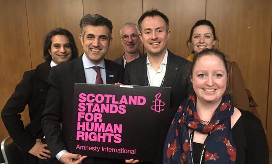 A group of people hold up an Amnesty International placard that says 'Scotland stands for human rights' A group of people hold up an Amnesty International placard that says 'Scotland stands for human rights'